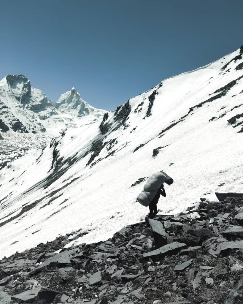 a porter carrying load up to the basecamp of Patangini Dhar