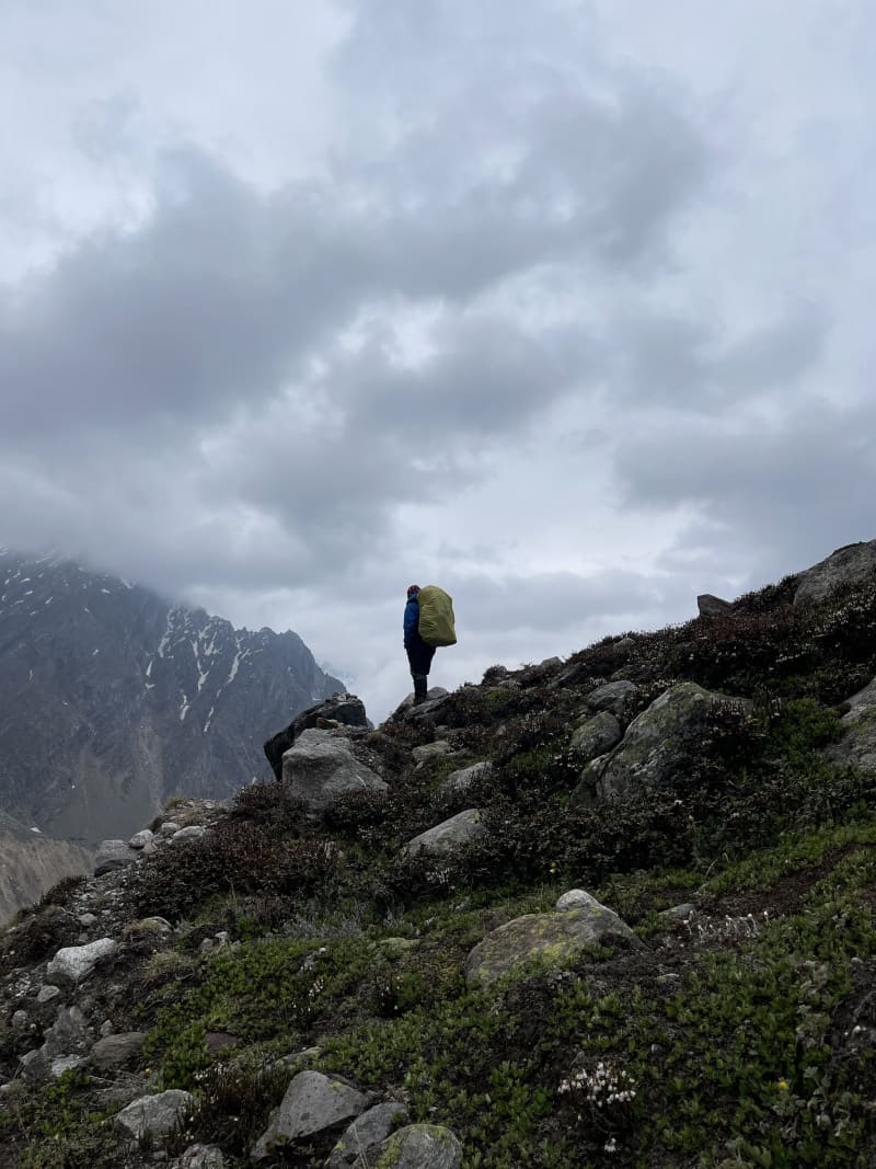 A trekker standing on a ridge near Khatling zero point camp